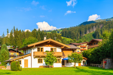 Fototapeta na wymiar Traditional house on green meadow in Kirchberg mountain village,on sunny beautiful summer day, Kitzbuhel Alps, Austria