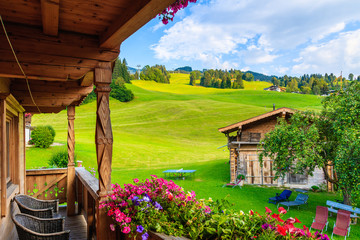 View of green meadow in mountains from typical wooden house balcony in Kirchberg village on summer day, Kitzbuhel Alps, Austria - obrazy, fototapety, plakaty