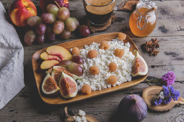 Homemade ricotta cheese , raspberries,figs , peach, honey. Healthy breakfast,
coffee. on serving board over rustic wooden
