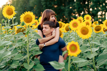 young loving couple in nature in summer on a background of sunflowers