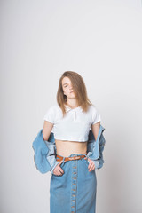 Cute girl on a white background in a photo Studio. Wearing a denim suit. Denim long skirt and...
