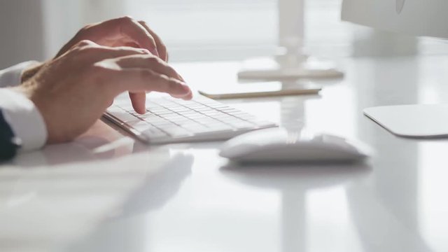 Close-up of male hands typing on computer keyboard