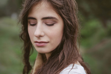 Fototapeta premium Portrait of brunette close-up, green background in nature, outdoor. Watching units. Natural make-up and hairstyle.