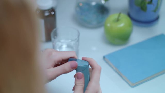 Asthma inhaler on table. Medical equipment on treatment of asthma attack. Close up of woman breathing asthma inhaler. Health care of asthmatic patient