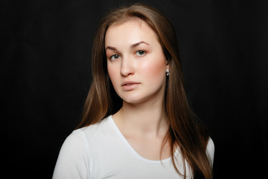 Youth, lifestyle and education concept. image of young hipster girl wearing blank white t-shirt and black jeans, black background.