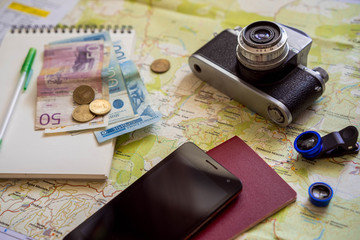 The concept of travel and the trip. Travel planning. Wooden table background on which are cards, camera, smartphone, money. 