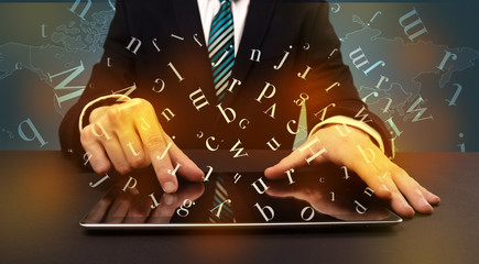 Young man in suit and formal clothing typing with letters around