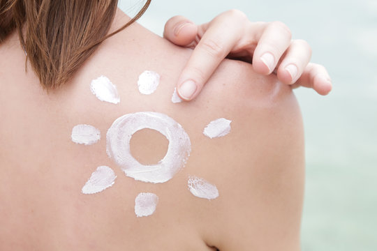 Woman with sun shaped sunscreen on her shoulder, skin protection concept