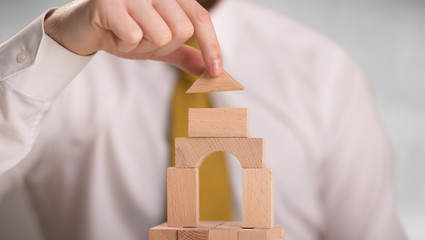 Young handsome businessman using wooden building blocks 