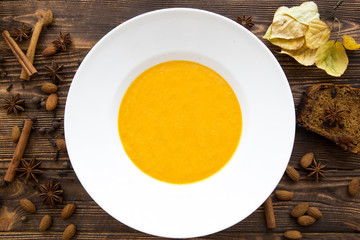 Tasty pumpkin cream soup, blended with spice and onion. Top view. Autumn mood, yellow leaves and...