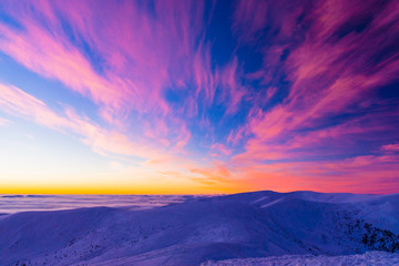 Amazing colorful sunset in mountains with absract wings shape of clouds
