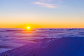 Amazing purple winter sunset over cloudy mountains