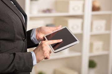 Business woman below chest using tablet in a homey environment 