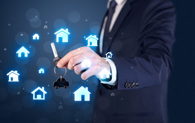 Businessman in suit holding keys with house graphics around and dark background
