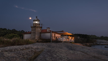  Illuminated lighthouse over the sea and the coast of Galicia © jesus