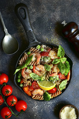Whole wheat fusilli pasta with shrimps and vegetables in a skillet.Top view.