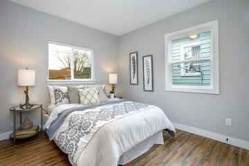 Fototapeta premium Beautiful gray and white bedroom with embroidery pattern bedding set