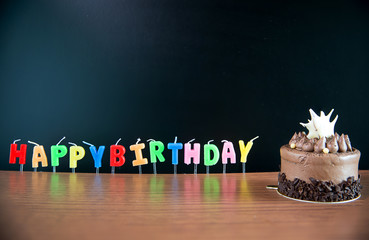 Candlestick alphabet word happy birthday and  Birthday Mini chocolate cake with blackboard on wooden floor. image for background, wallpaper, copy space and greeting card