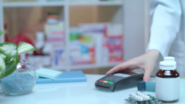 Mobile NFC payment for medical pills. Customer hand paying through mobile phone pos terminal with NFC technology at drugstore. Close up of medicament pill buy with apple pay. Pharmacist sell pills