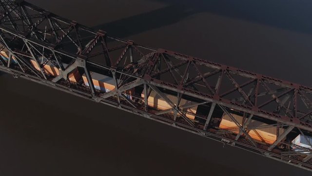 An aerial bird's eye view looking straight down on a cargo train traveling on a railroad bridge over the Ohio River.  	