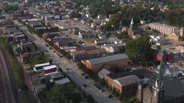 Reverse Aerial establishing shot of a small Pennsylvania town's business district on a late summer day. Pittsburgh suburbs.  	