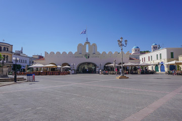 Fototapeta premium Kos, Greece: Cafes and shops lie around the edges of Eleftherias Square, with an indoor market hall at the center, in Kos Town.