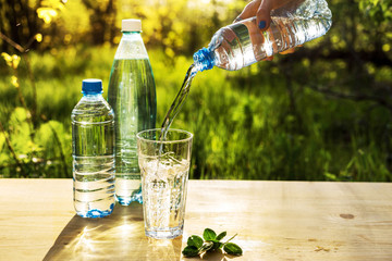 The life-giving power of water. A man's hand pours a bottle of drinking water into a glass on a...