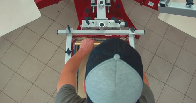 OVERHEAD Silk screen printing process - making a print on a t-shirt. 4K UHD