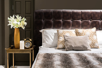 Luxury bedroom with brown color tone and flower vase and clock on table side