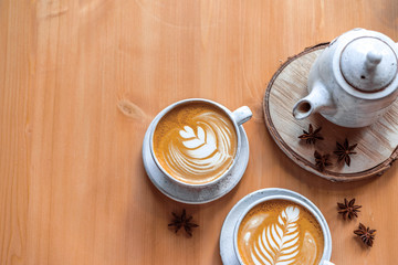 two cups of cappuccino with a beautiful pattern on milk foam. Wooden table with space for text. The view from the top.