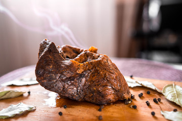 Baked beef shank with spices, close-up on the table, a hot dish with smoke from the oven