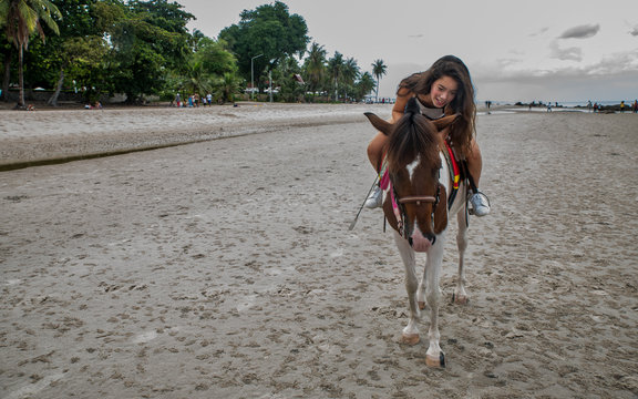 Young woman on beach hugging horse