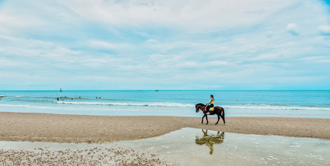 Young woman on beach riding horse