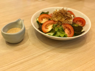 Tofu Salad topped with small crispy fish dish and White sesame dressing on the wooden table.Healthy menu for diet. Traditional Japanese food salad. top view and copy space