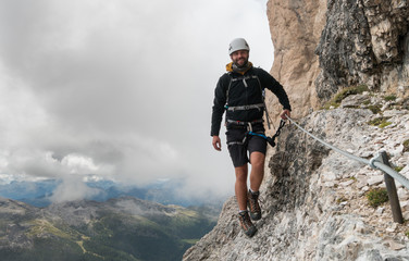 young male mountain climber on a steep and exposed Via Ferrata in Alta Badia in the South Tyrol in the Italian Dolomites
