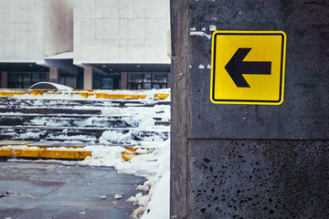 Yellow arrow for the disabled near high stairs in the street in winter in the snow