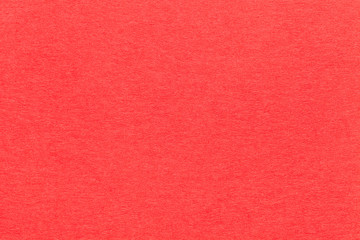 Texture of old bright red paper closeup. Structure of a dense cardboard. The carmine background