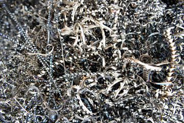 Tangled twisted pile of discarded industrial scrap metal waste, spiral shavings and filings.
