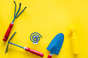 Mosquito protection for garden. Mosquito coil and spray near garden tools on yellow background top view copy space