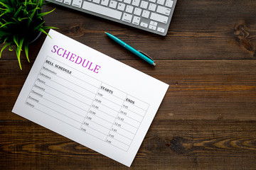 School student's schedule with time of lessons on dark wooden office desk with computer keyboard top view copy space
