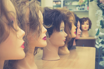 Wigs on mannequin heads in a row.
