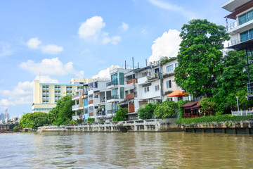 Fototapeta na wymiar riverside residential buildings with blue sky and clouds background at Chao Phraya river, Bangkok, Thailand