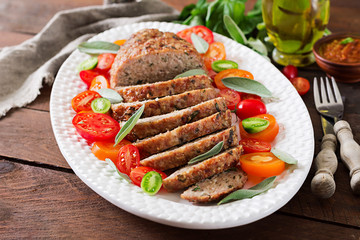 Tasty homemade ground  baked turkey meatloaf in white plate on wooden table. Food american meat loaf.