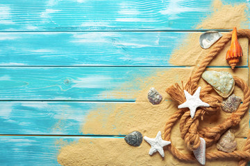 sea rope with many different sea shells on the sea sand on a blue wooden background. Top view