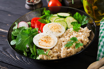 Healthy salad of fresh vegetables - tomatoes, cucumber, radish, egg, arugula and oatmeal on bowl. Diet food.