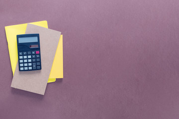 Top view over a school supplies as calculator and notebooks placed from left side of a brown background. Back to school concept. Office supplies flat lay