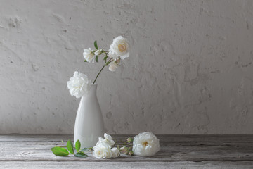 white roses in vase on old background