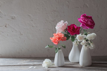 roses in white vases on old background
