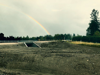 Drizzle on the windshield while driving in rain. Wet road and rainbow in the sky.