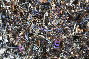 Background of tangled twisted pile of colorful industrial scrap metal waste debris, spiral shavings and machine filings